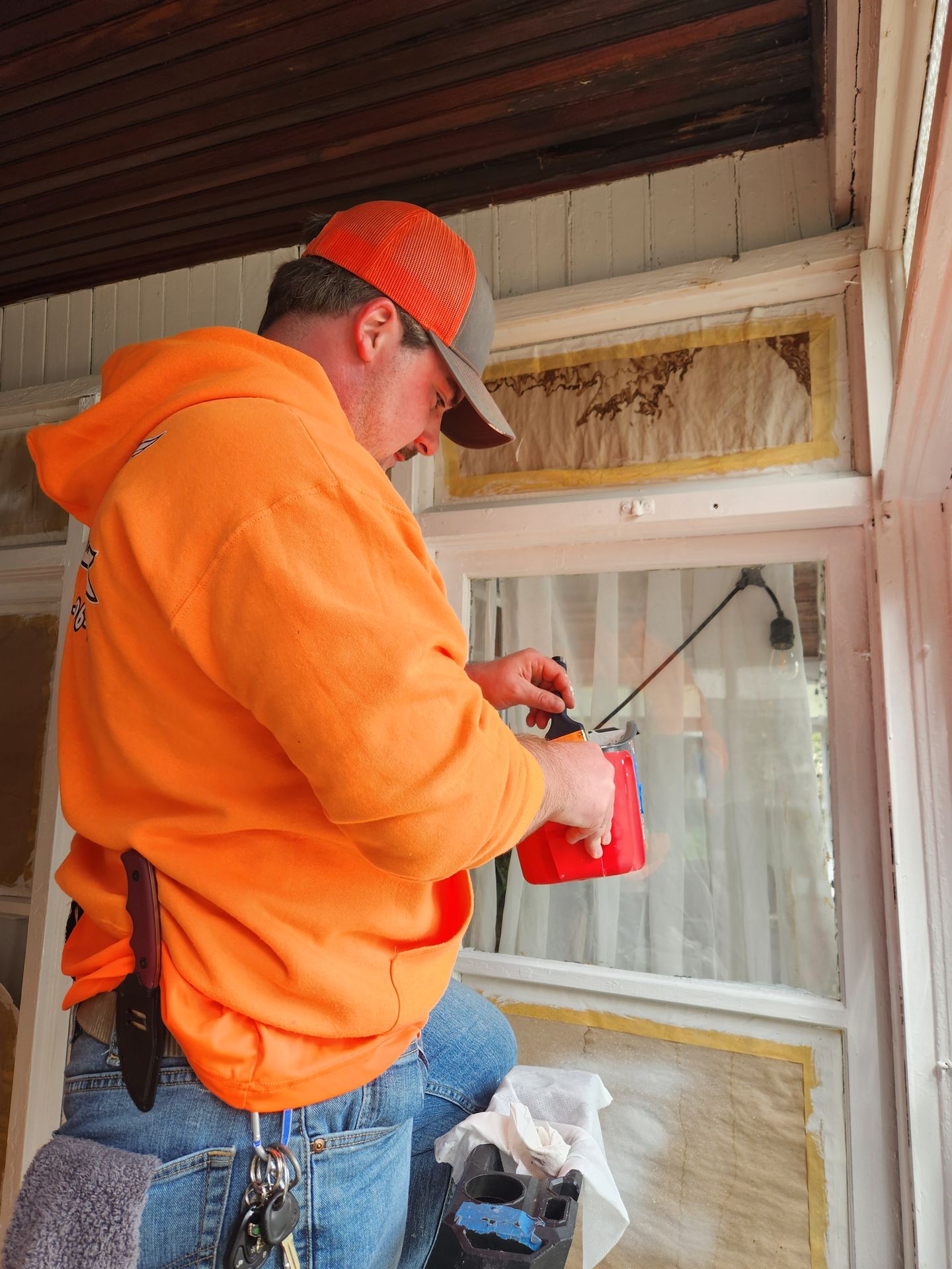 Side by Side technician in an orange company hoodie repairing window trim