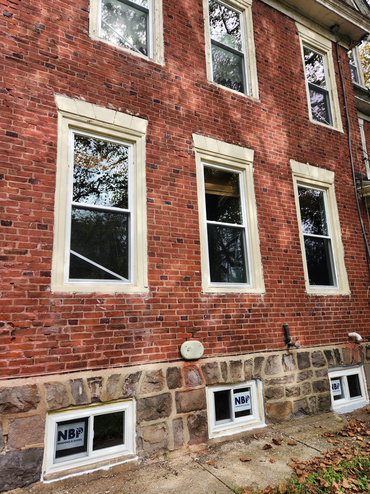 New basement windows installed in a stone foundation of a brick building